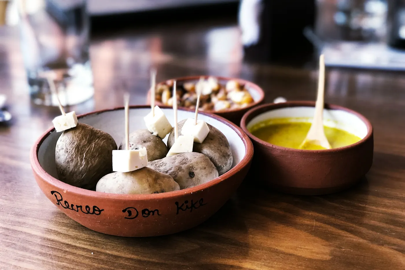 A clay dish of cheese cubes beside a bowl of olive oil