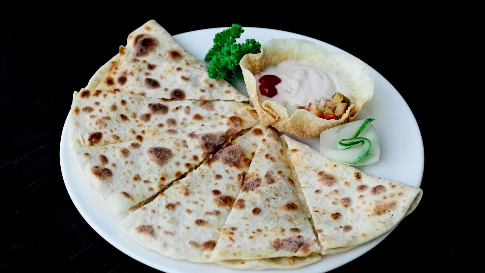 A cheese quesadilla cut into wedges on a white plate