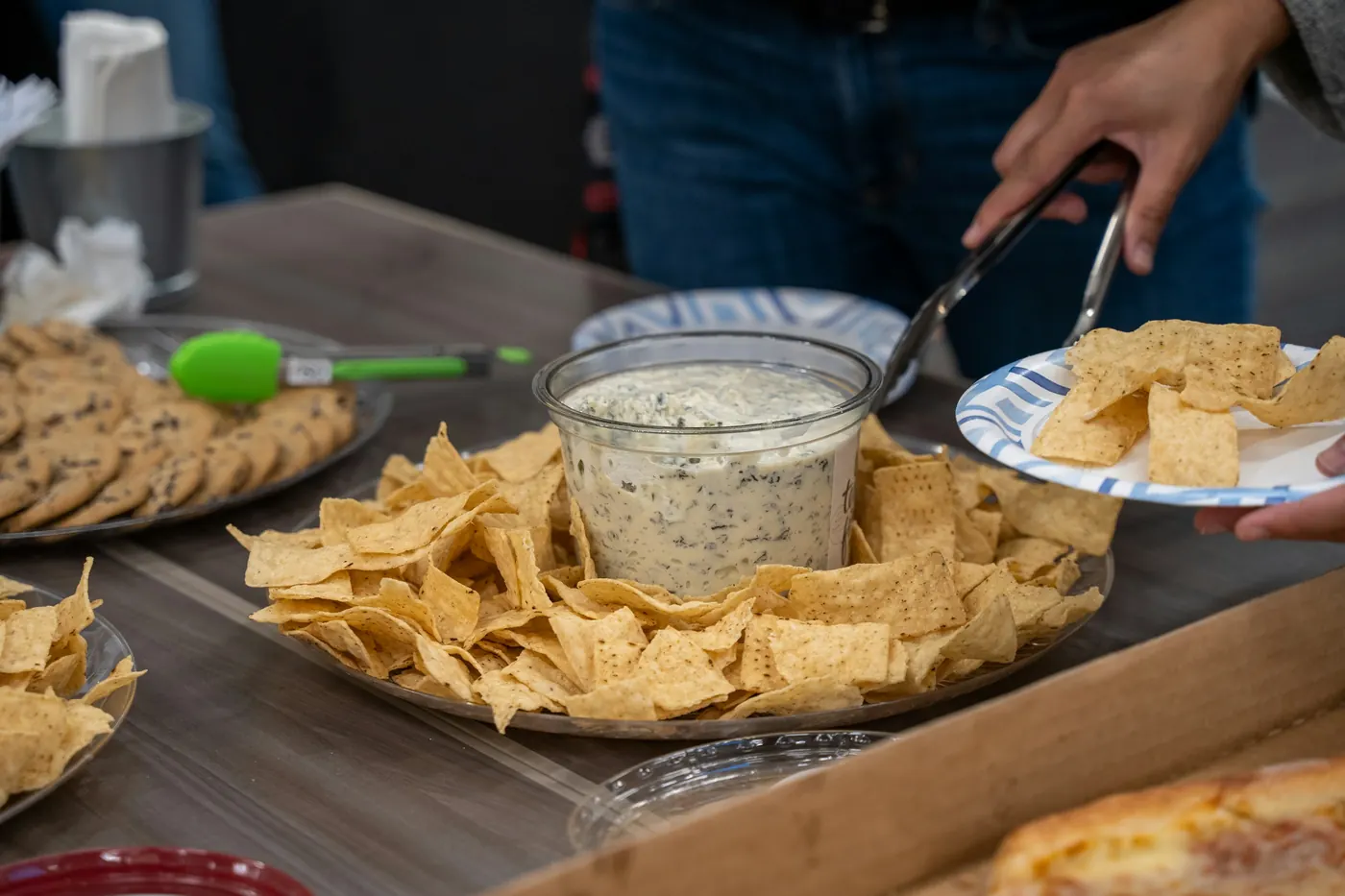 Tortilla chips and a bowl of dip being set down on a table