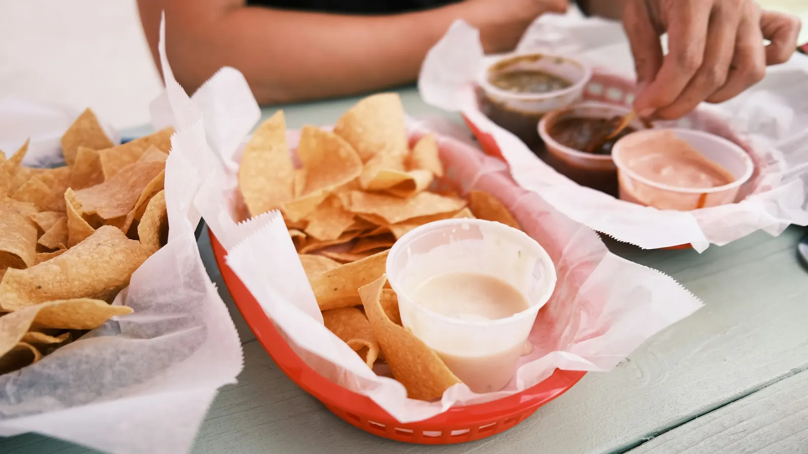 A basket of tortilla chips and small bowls of salsa on a restaurant table