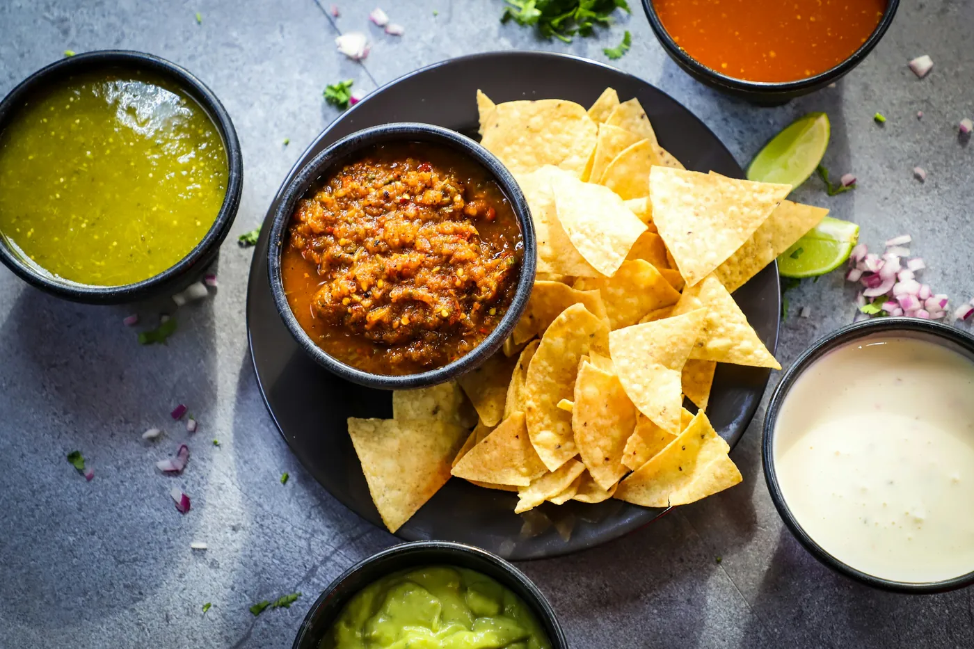 Tortilla chips served with bowls of red salsa, green salsa and queso