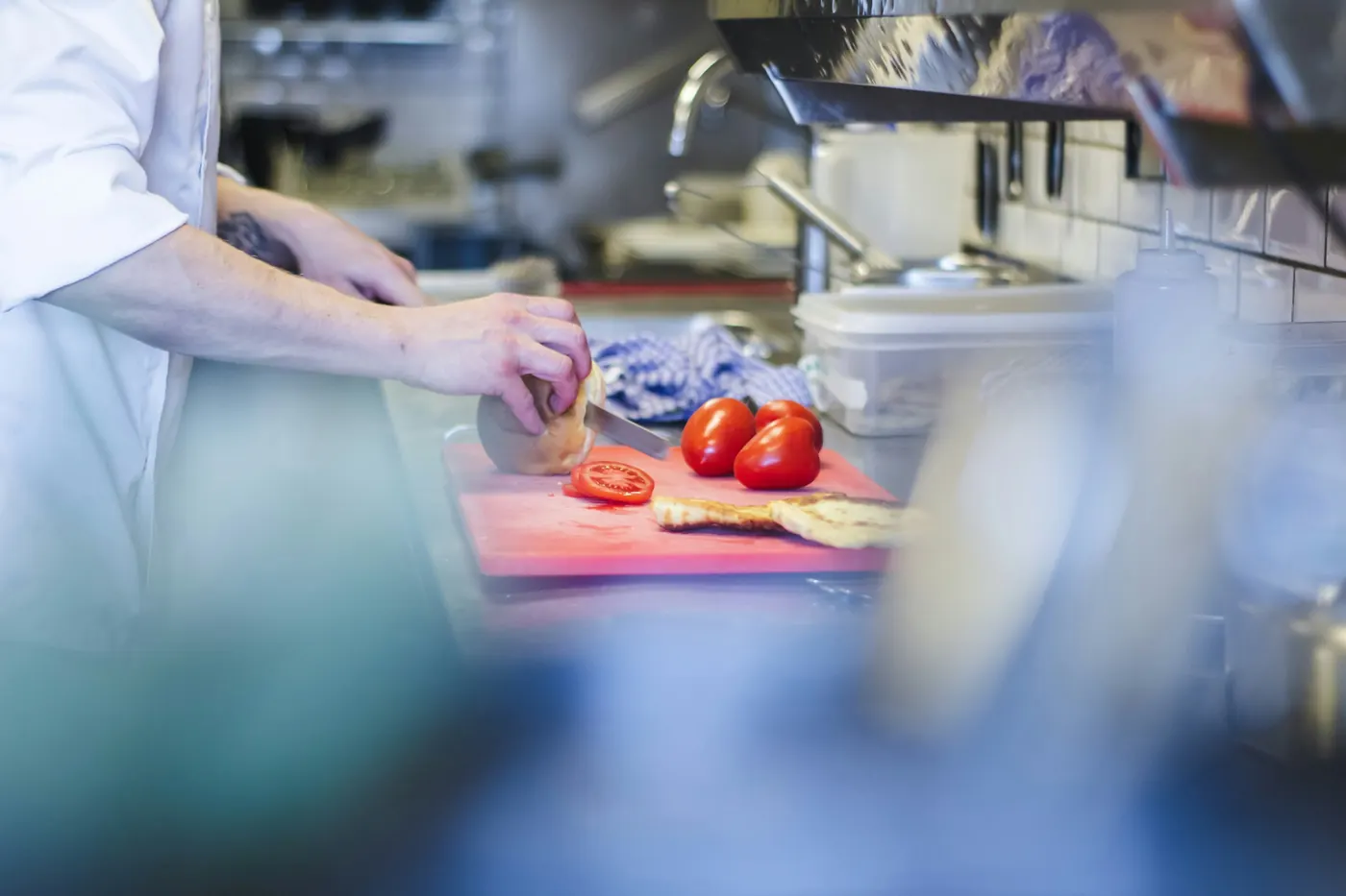 Hands chopping fresh tomatoes and vegetables on a board