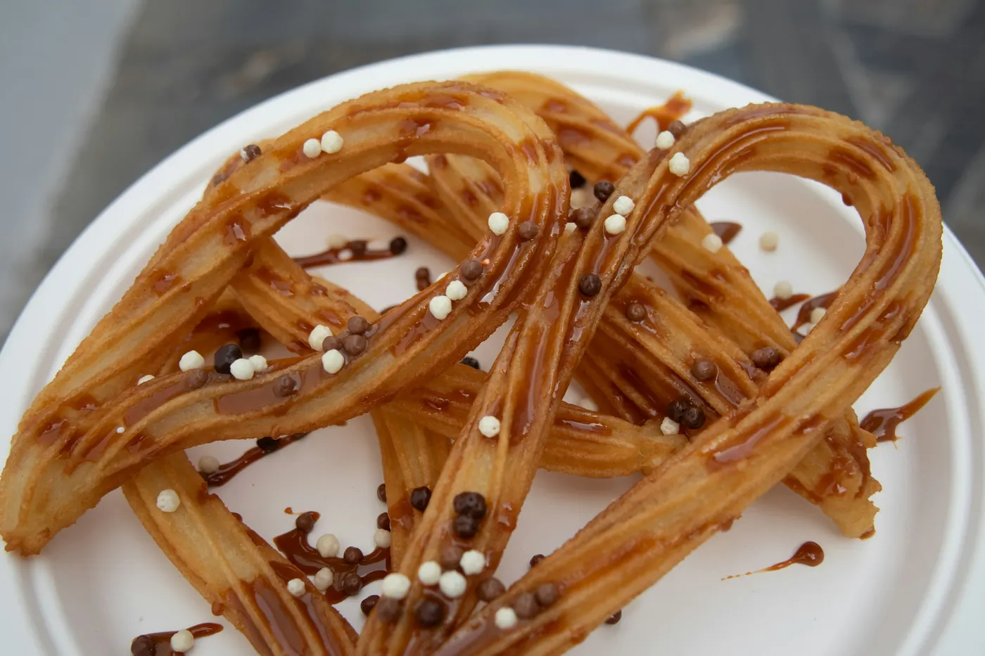 Long churros arranged on a plate with chocolate drizzled over