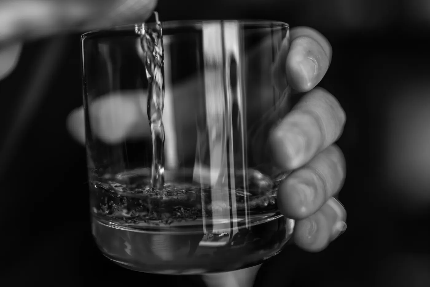 A clear spirit being poured into a small glass