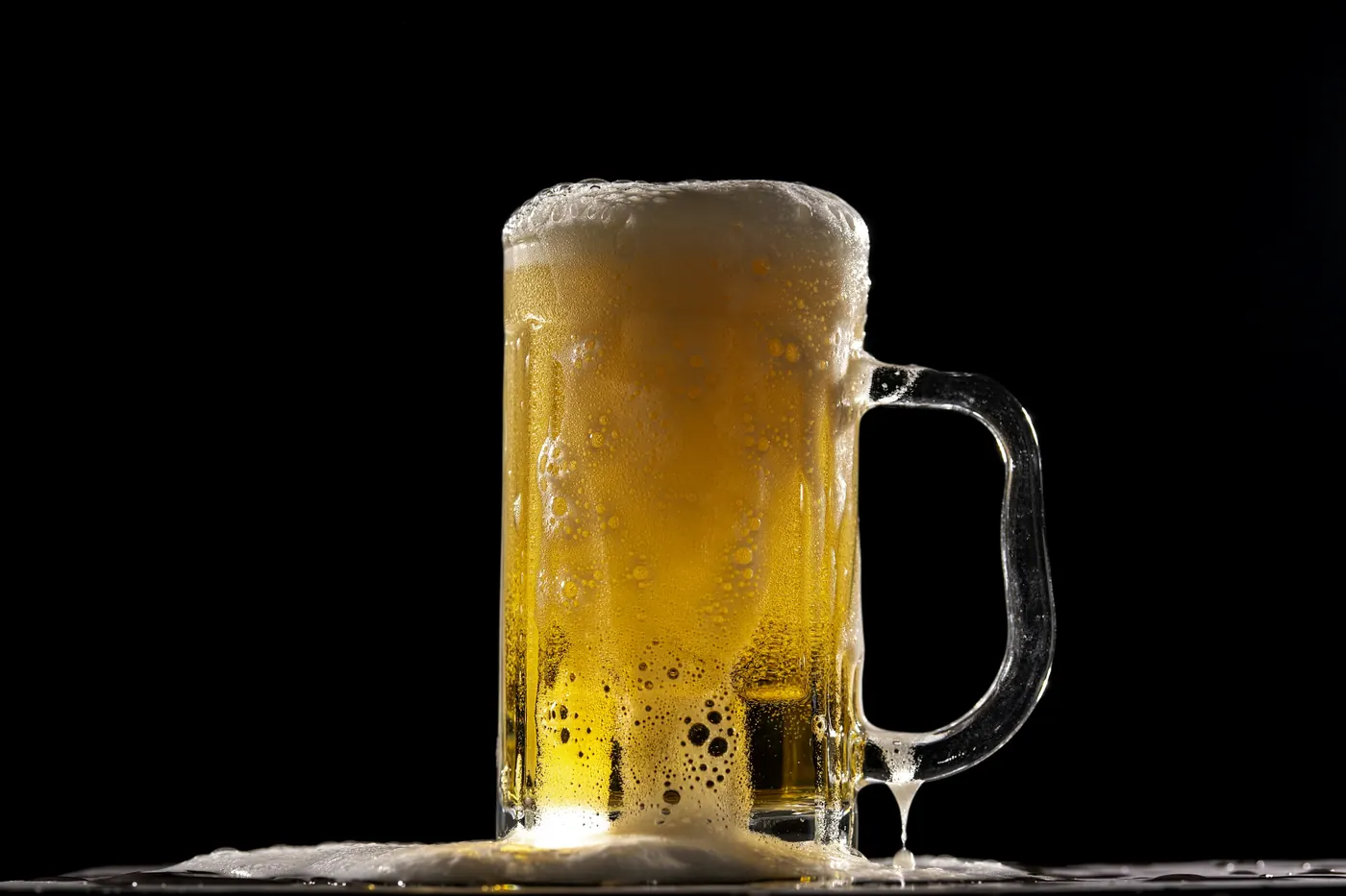 A cold glass mug of pale beer with a thick head of foam