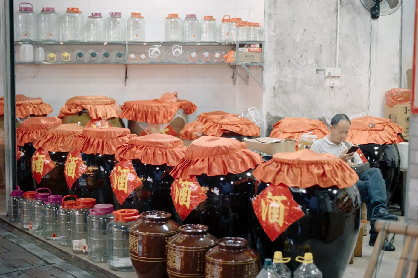 Rows of large glass jars with cloth covers at a market