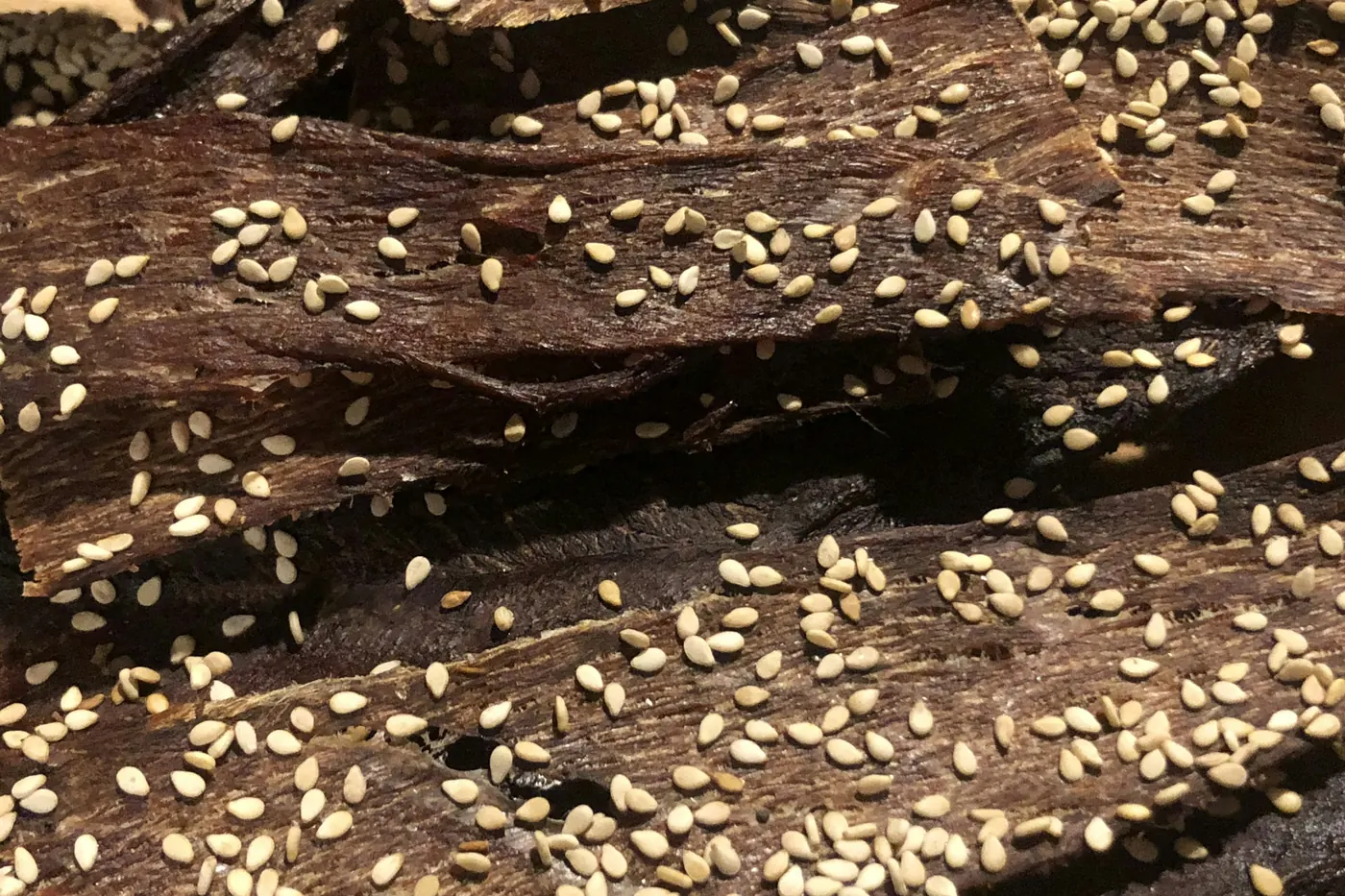 A close view of dark sauce scattered with sesame seeds