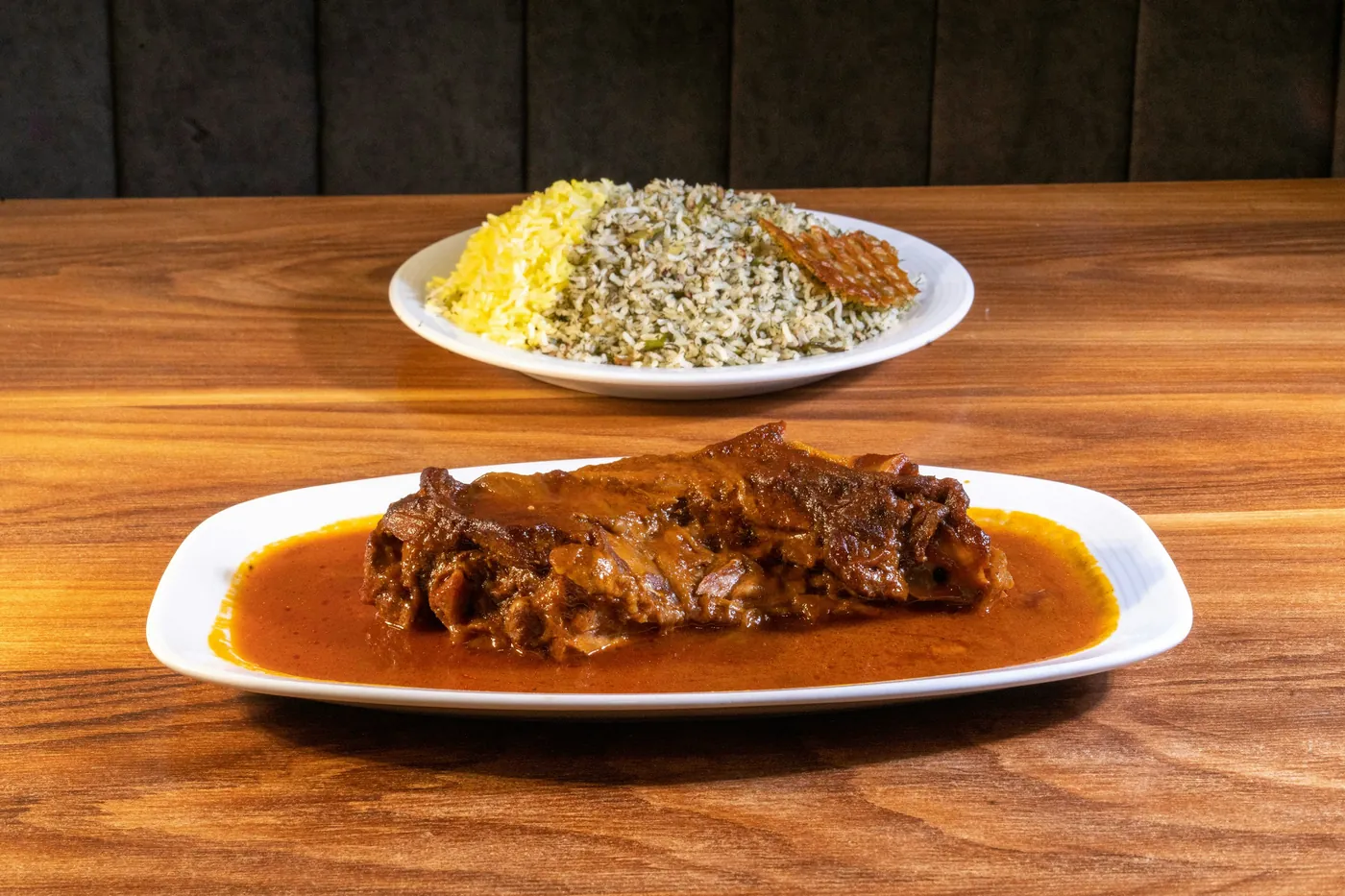 Braised meat in a dark brown sauce served with rice on a white plate