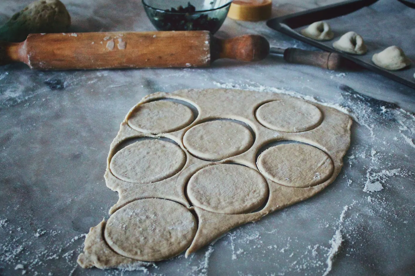 Rounds of dough cut out on a floured wooden surface