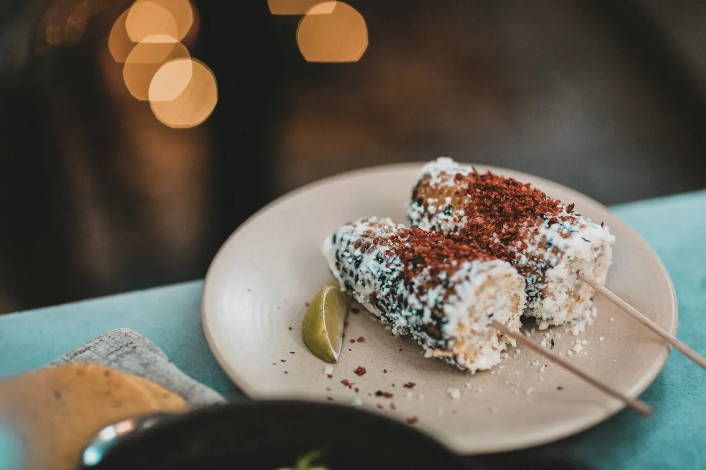 A cob of corn on a wooden stick, coated and dusted with chile powder