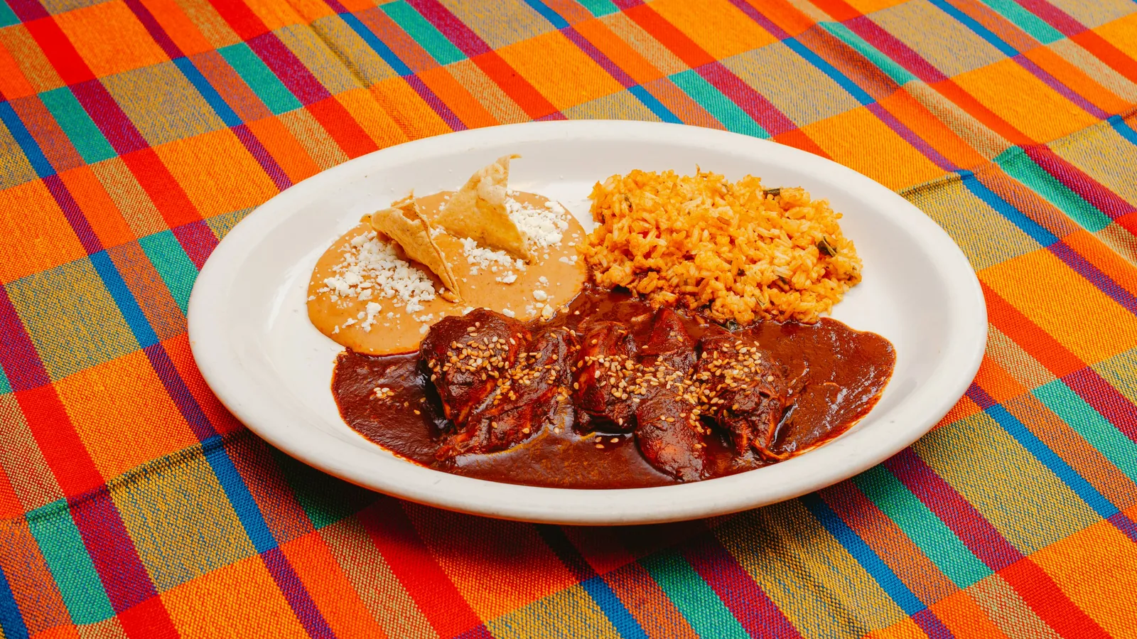 Enchiladas covered in red chile sauce, served on a plate with rice