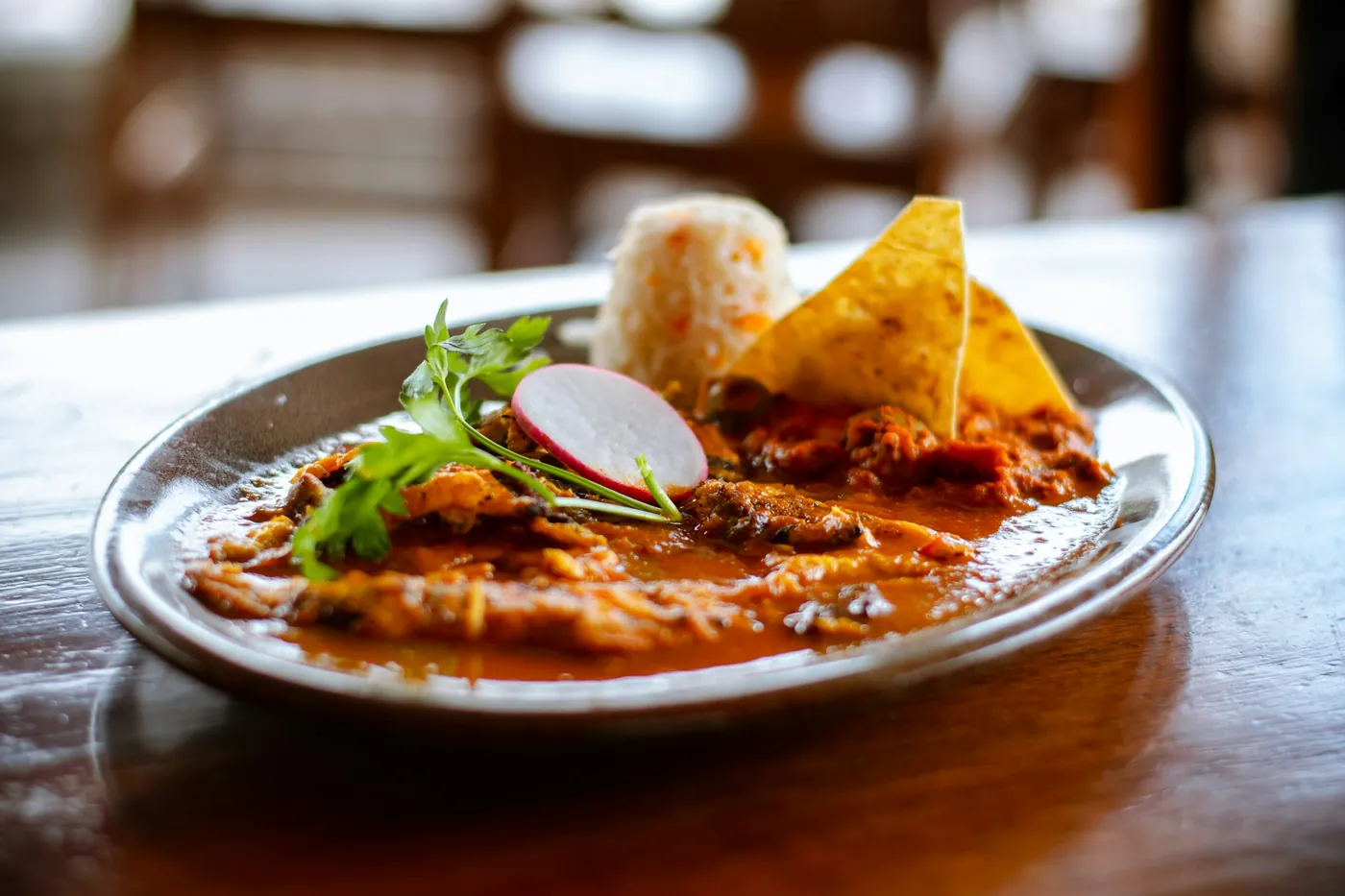 Enchiladas covered in red sauce and garnished, served on a white plate