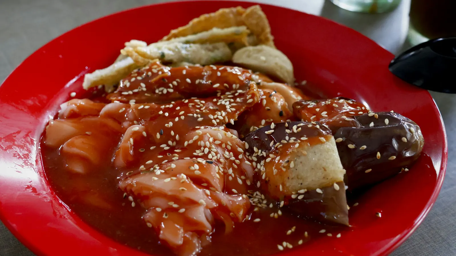 Enchiladas covered in a dark brown sauce and scattered with sesame seeds
