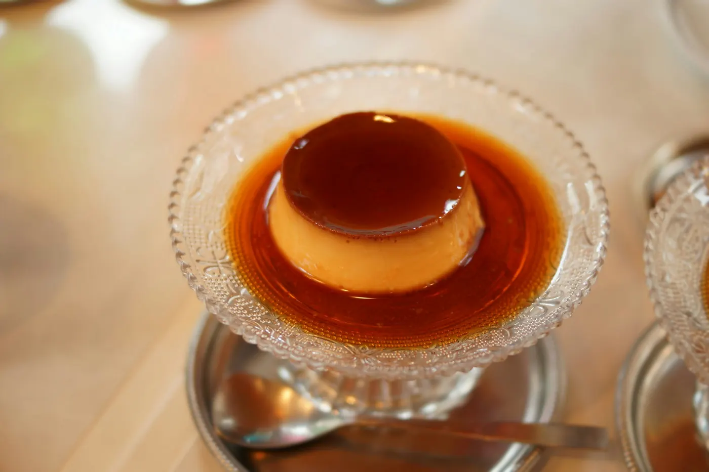 A set custard served in a footed glass dish with dark syrup over it