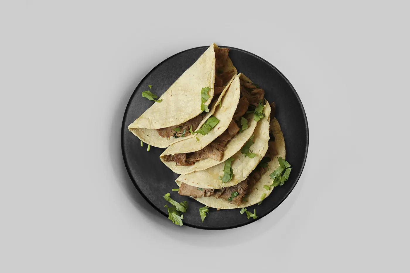 A stack of plain folded corn tortillas on a dark plate