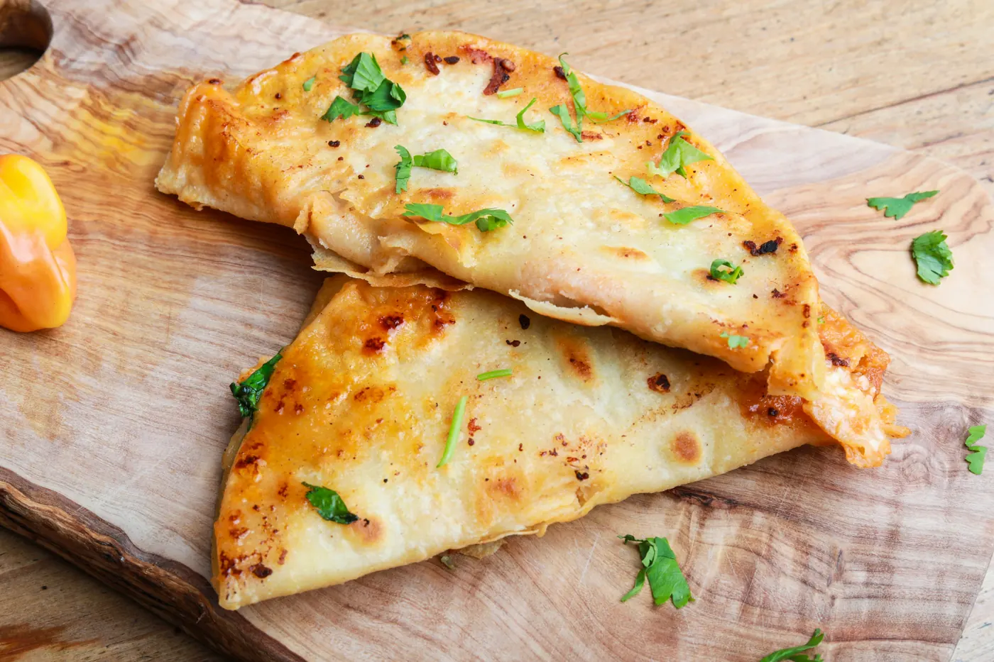 Folded quesadillas with melted cheese on a wooden board