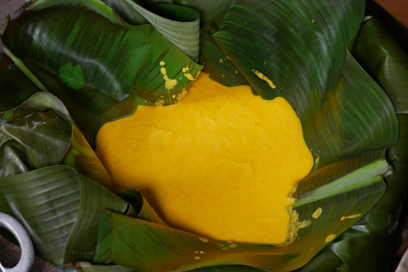 Food sitting inside an opened banana leaf wrapper