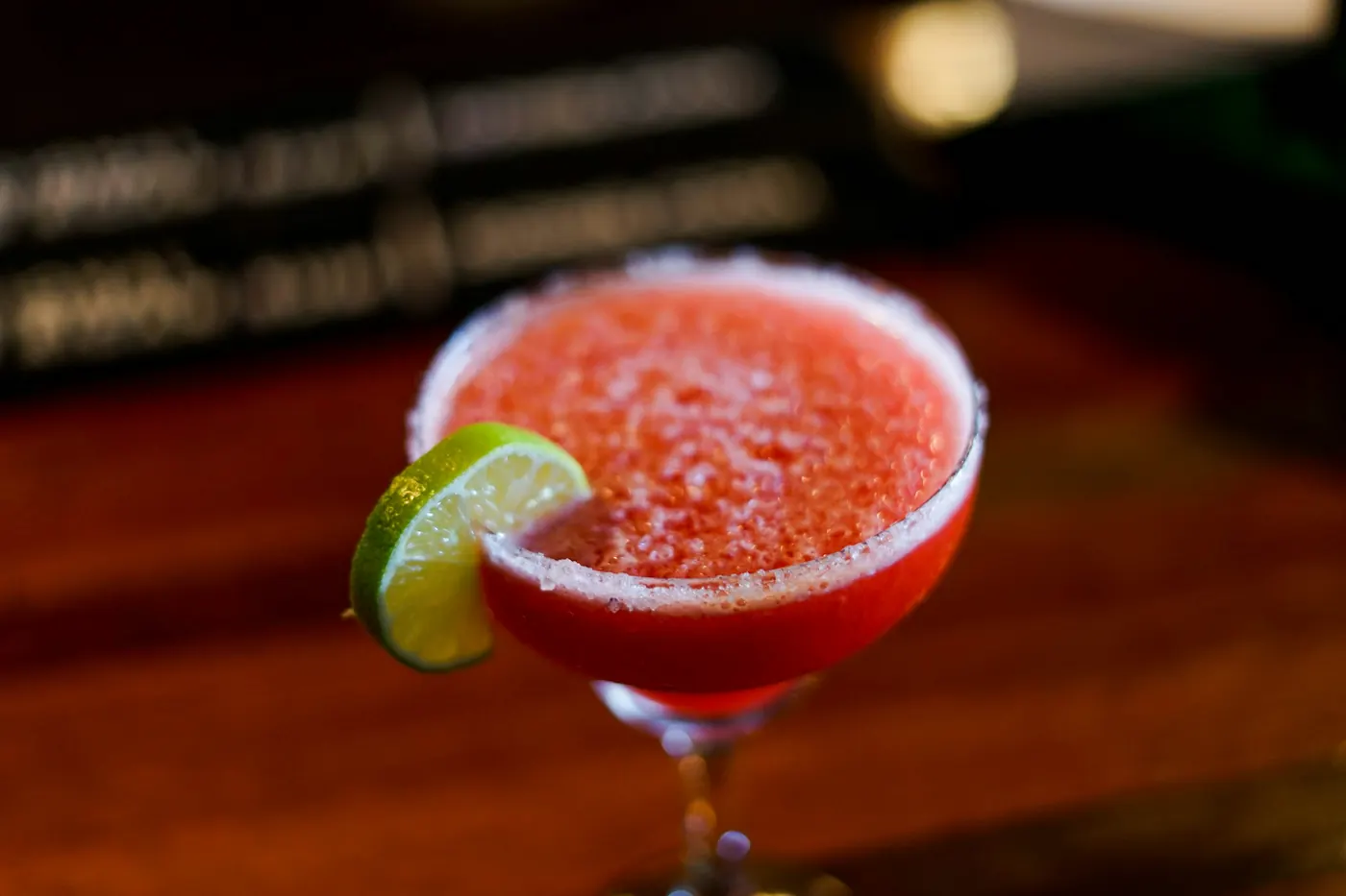 A frozen strawberry margarita in a coupe glass with a lime wedge
