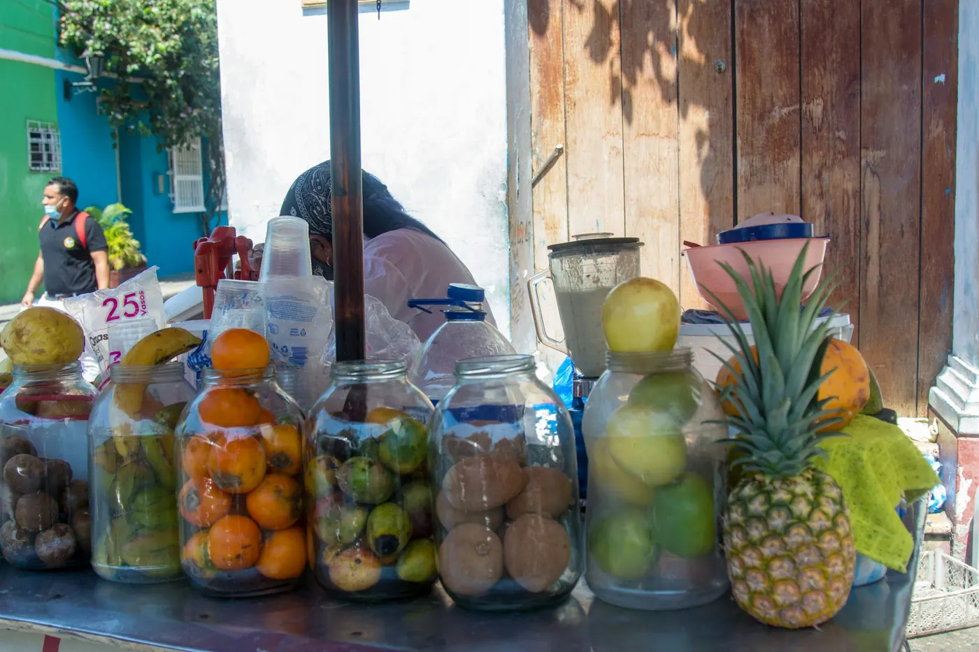 Glass jars packed with cut fruit at a street stall