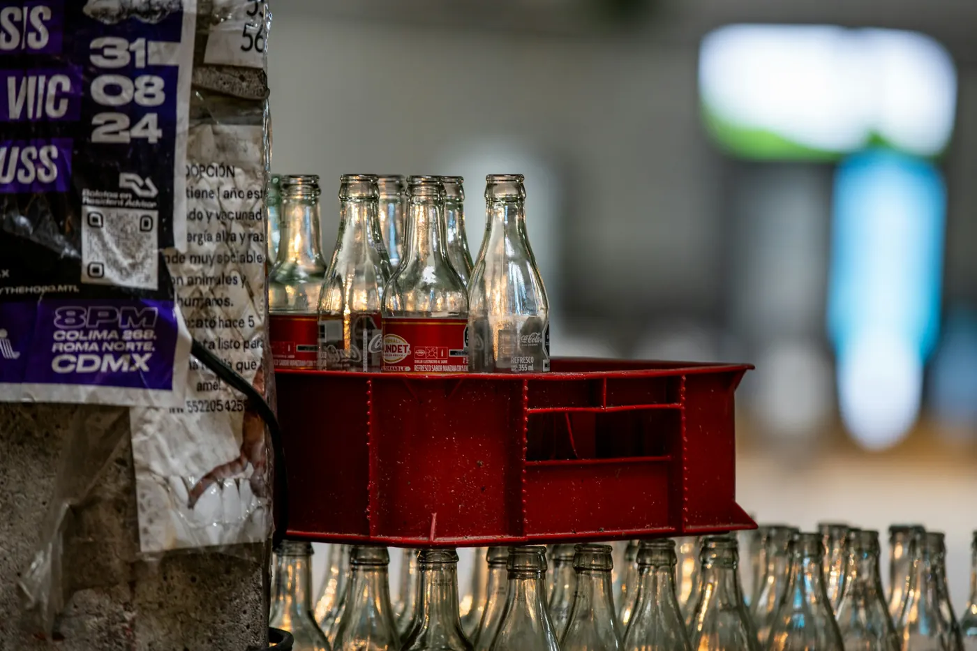 Glass bottles stacked in crates beside a wall on a Mexico City street
