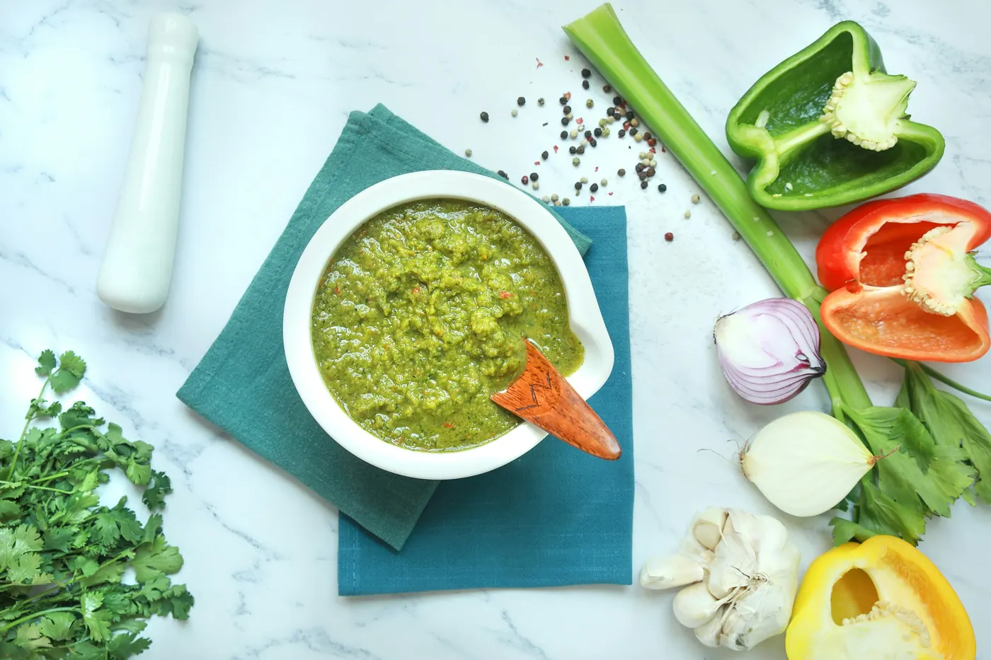 A bowl of green salsa surrounded by fresh vegetables
