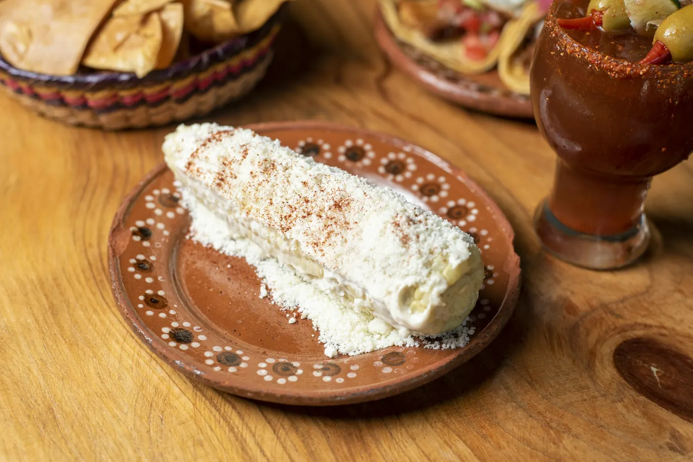Grilled corn coated in crema and dusted with crumbled white cheese