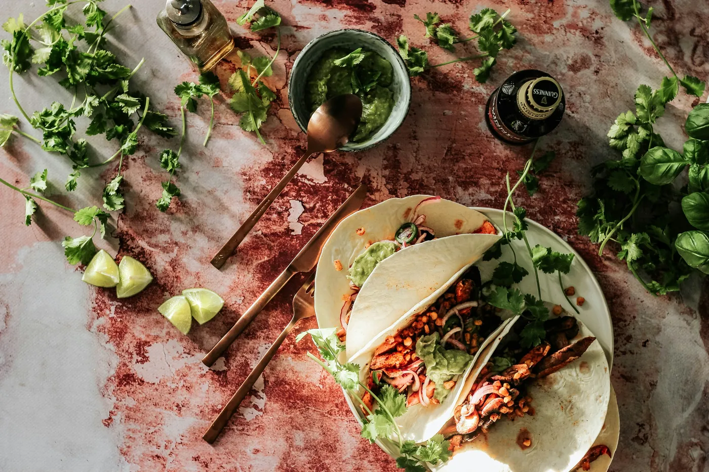 Tacos filled with grilled sliced meat and fresh herbs on a stone surface