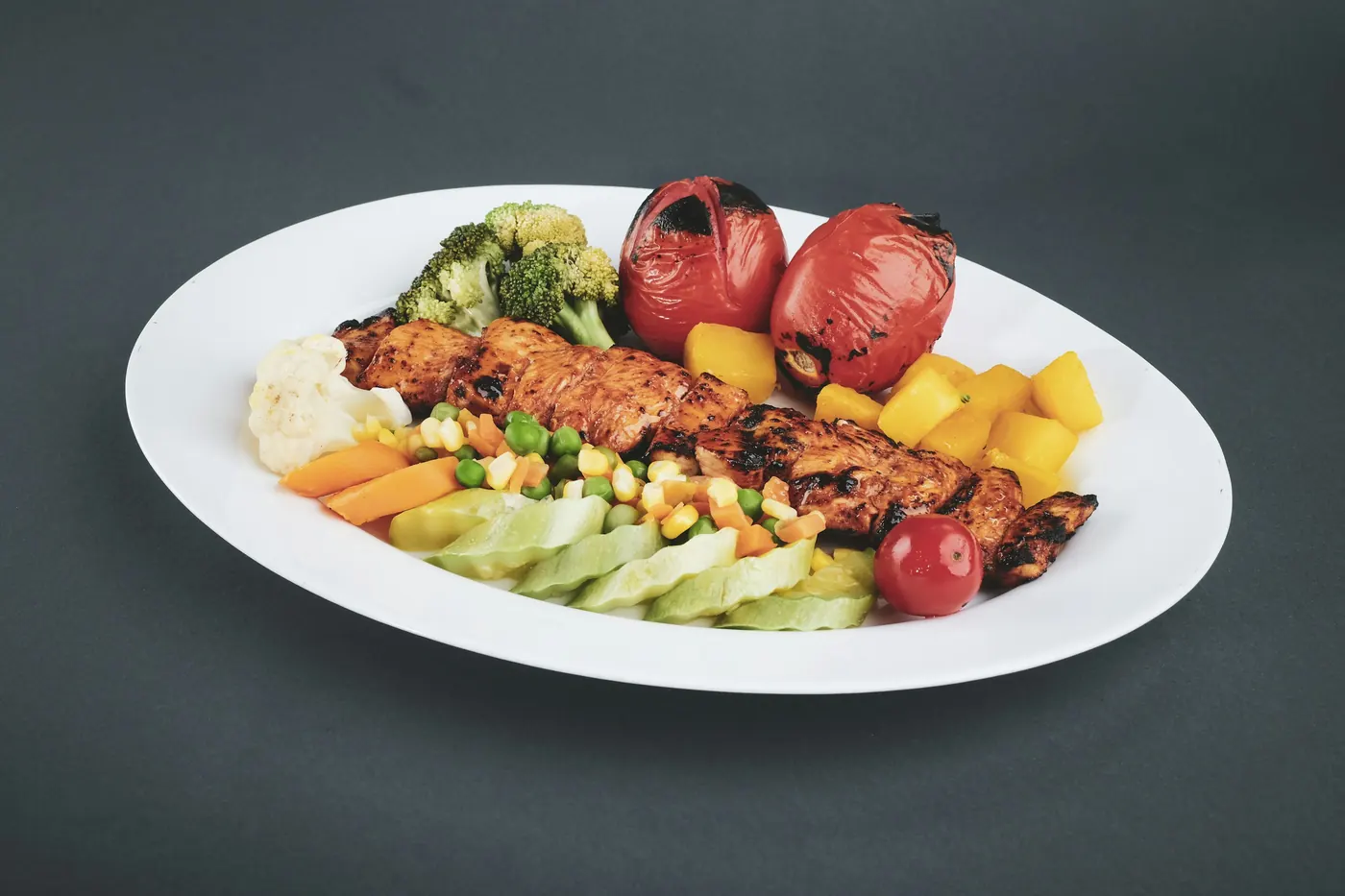 Grilled protein plated with roasted vegetables on a white plate