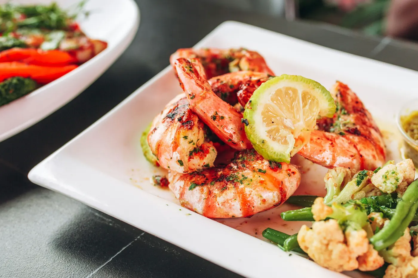 Grilled shrimp arranged on a white plate with lime slices