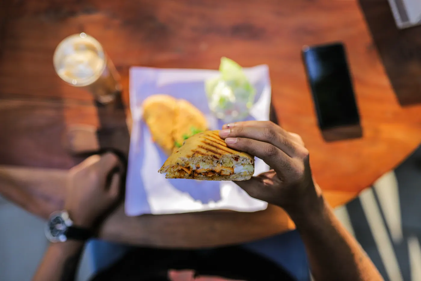 Hands holding a folded tortilla over a wooden table