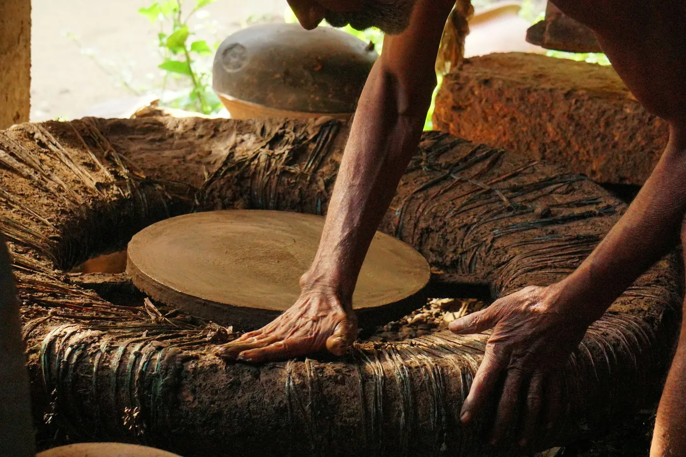 Hands working a heavy stone and timber press
