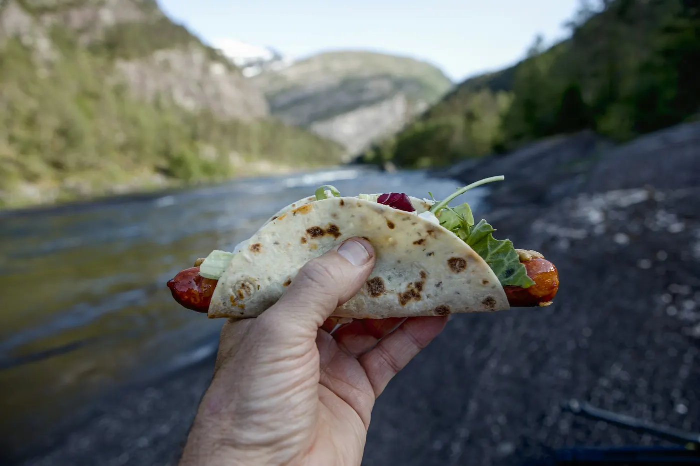 A hand holding a filled taco outdoors