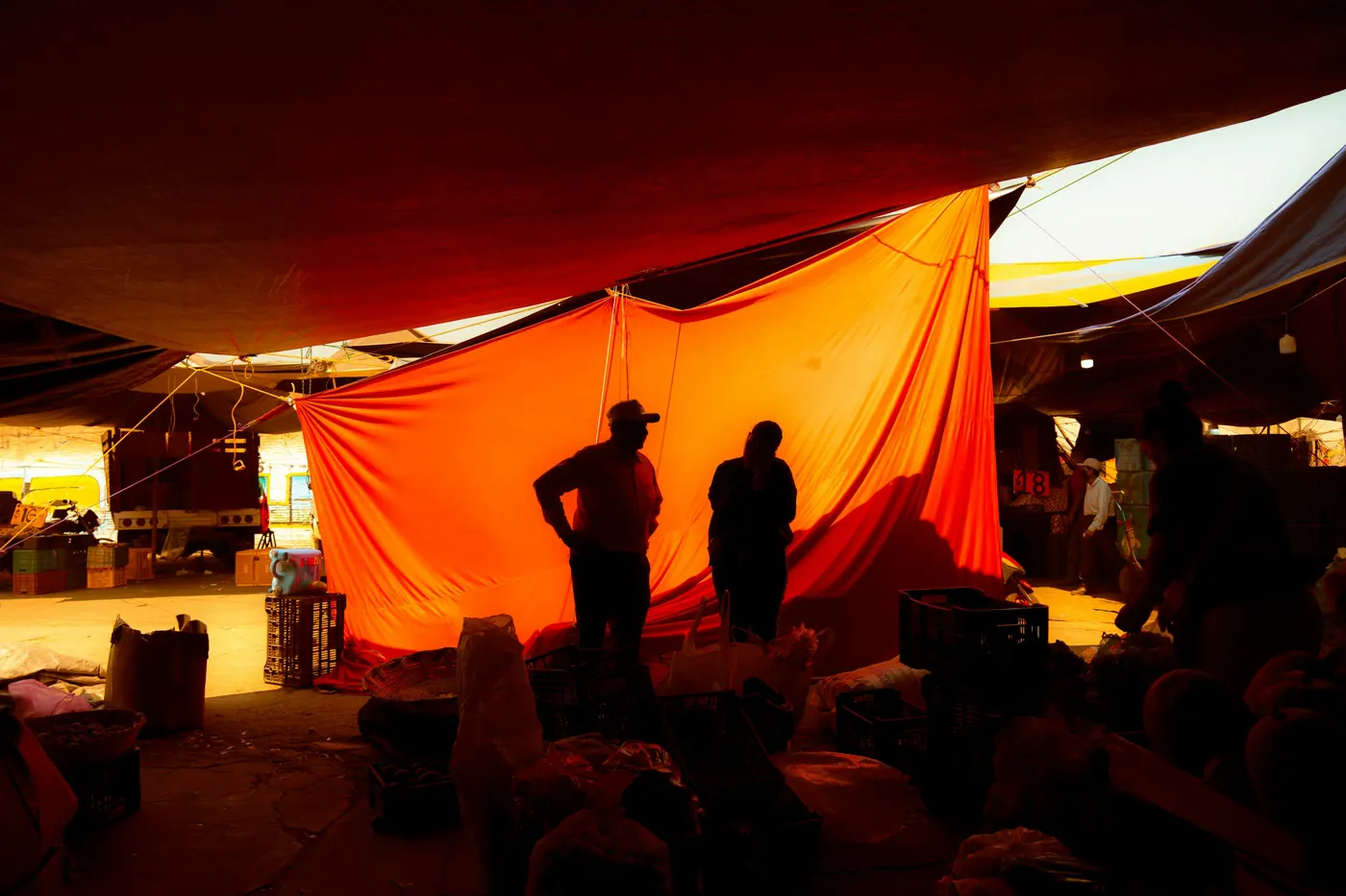 The interior of a covered market lit orange through fabric awnings
