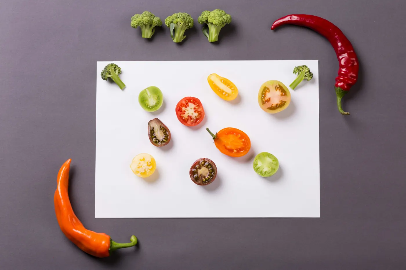 Many small chile peppers of different shapes and colors arranged on a white sheet