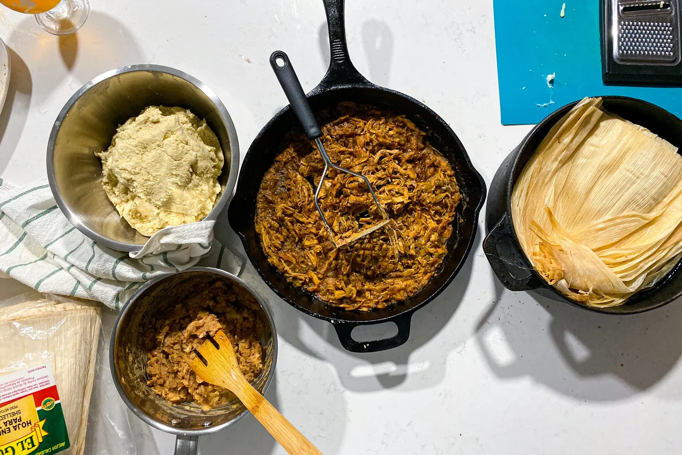 Bowls of masa and seasoned filling beside soaked corn husks