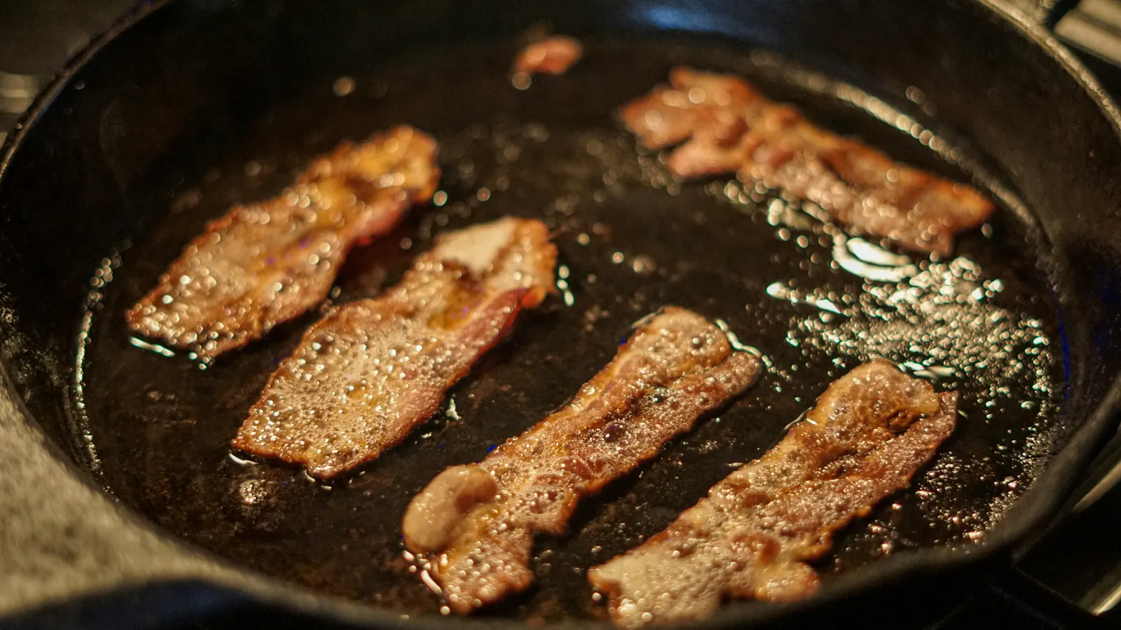 Strips of meat searing in a cast iron skillet