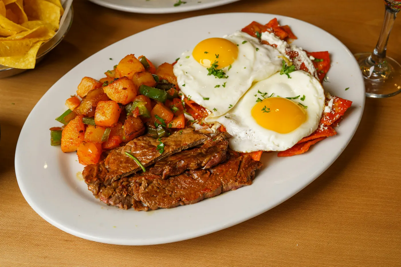 A breakfast plate of fried eggs, seasoned potatoes and grilled meat
