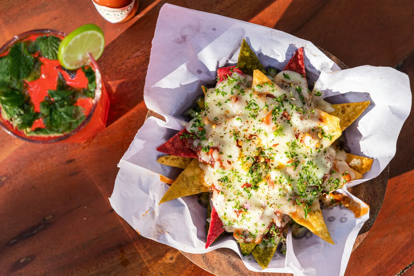 Nachos served in paper lining with melted cheese and herbs