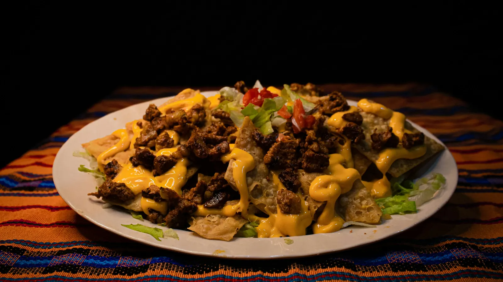 A plate of nachos covered in melted yellow cheese and seasoned beef
