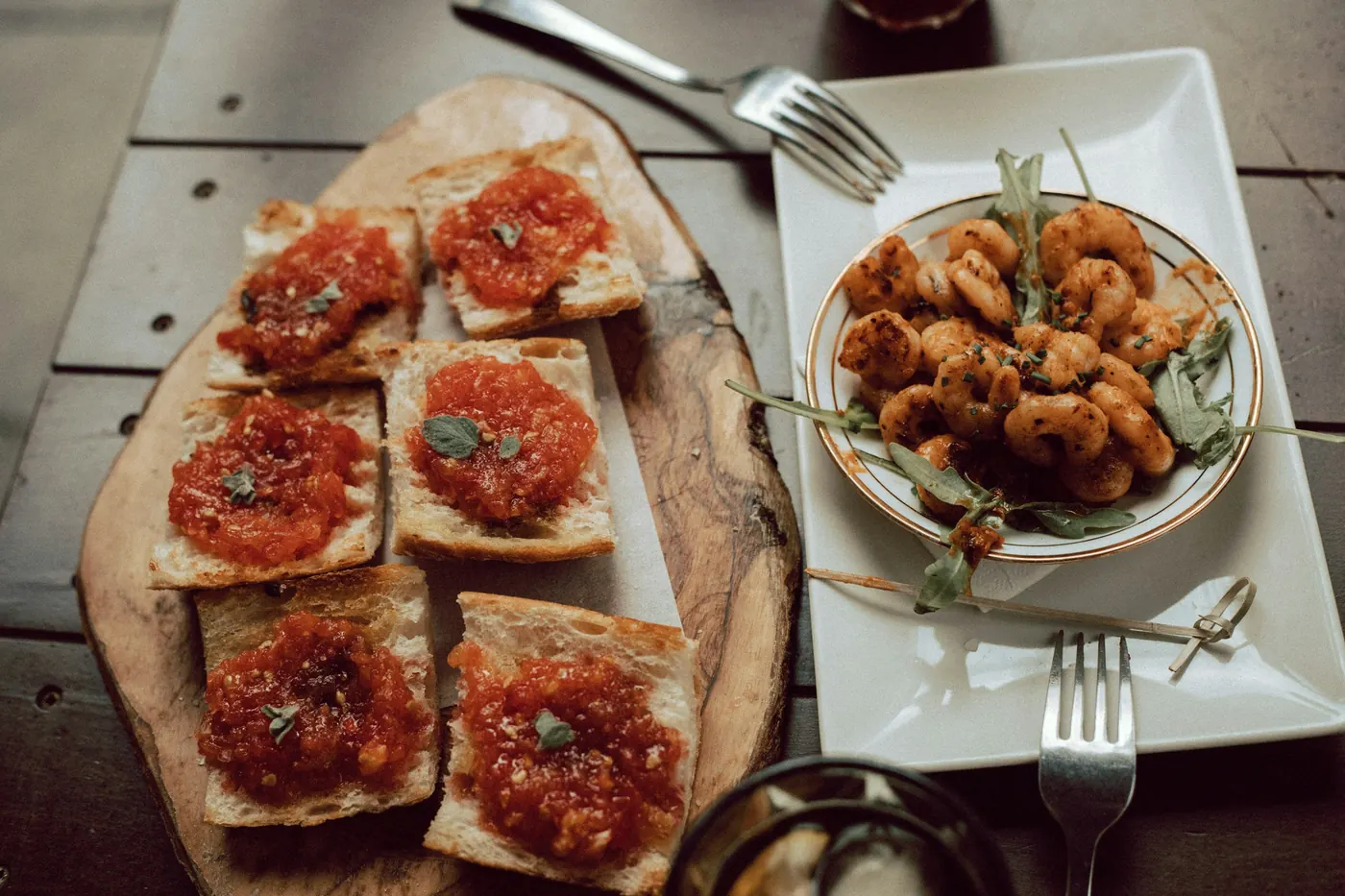 Toasted bread topped with tomato beside a plate of fried squid