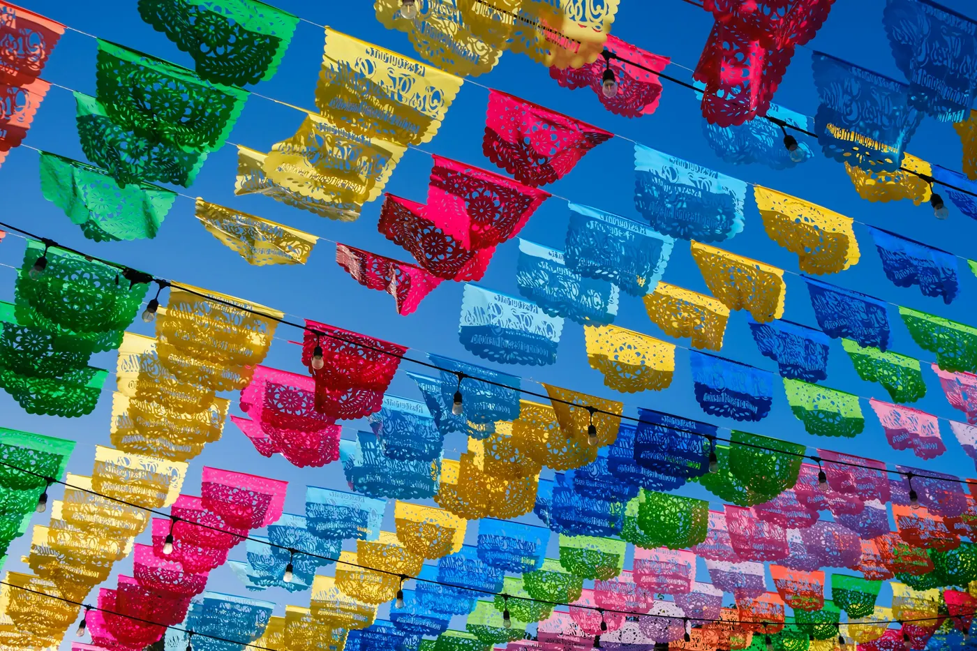 Colorful cut-paper banners strung against a bright blue sky