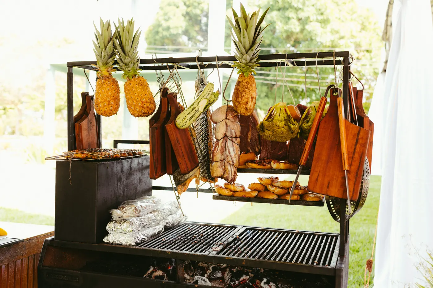 Whole pineapples mounted above meat roasting on a spit