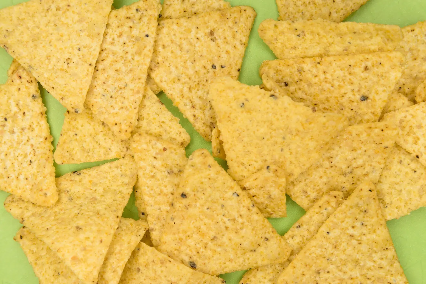 A scattered layer of plain triangular tortilla chips