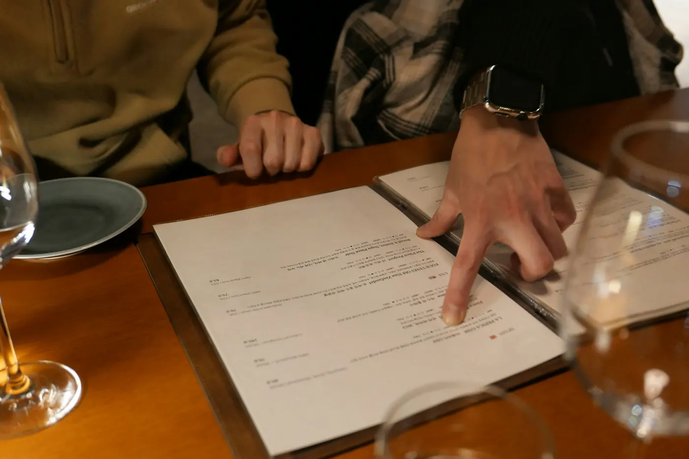Hands resting on an open menu, one finger pointing at an item