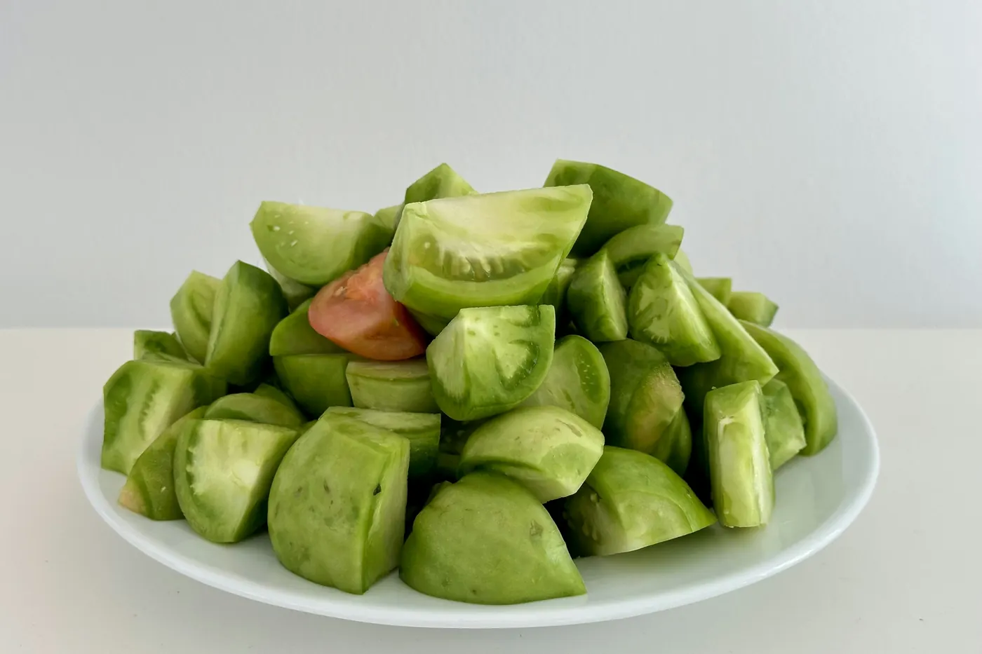 Quartered green tomatillos piled on a white plate