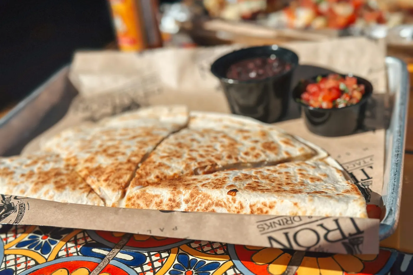 Quesadilla wedges on a wooden board with small bowls of salsa alongside