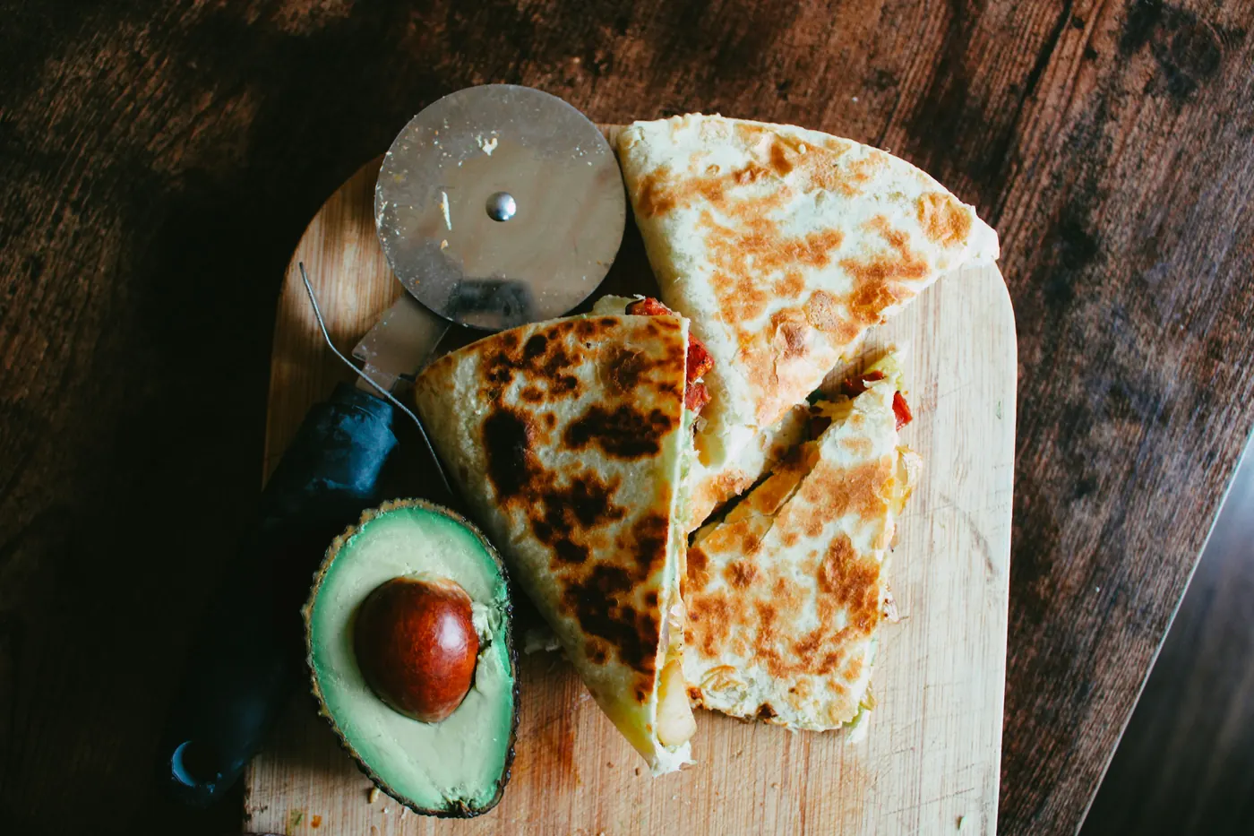 Quesadilla wedges beside a wheel cutter and half an avocado