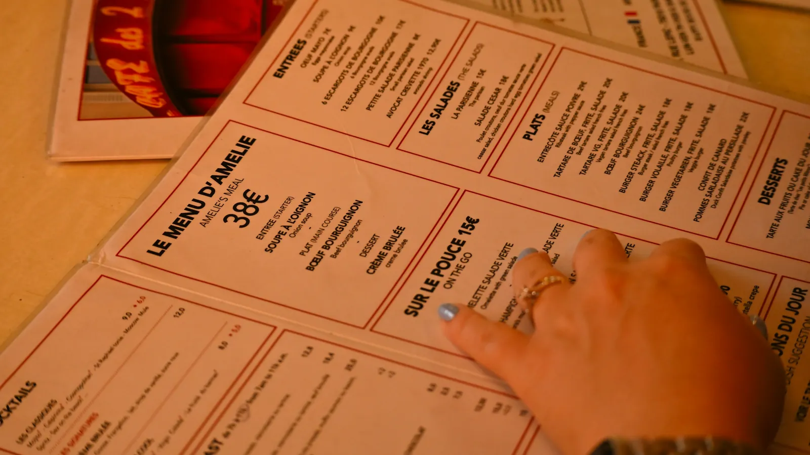 A person reading a printed restaurant menu at a table