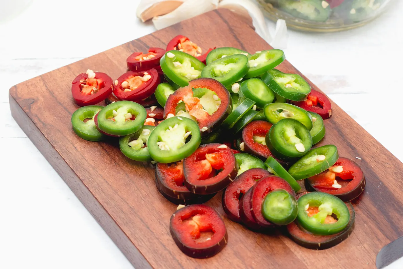 Sliced red and green jalapeno rounds on a cutting board