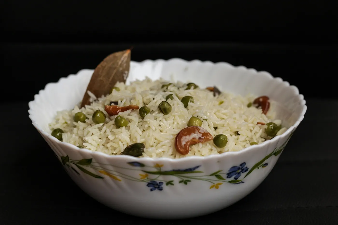 A bowl of rice cooked with peas and pieces of vegetable